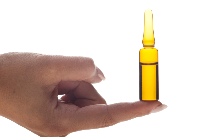 Hand holding a Vitamin C ampoule on a white background