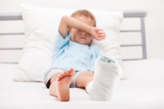 Small boy with a plaster bandage on his leg. 