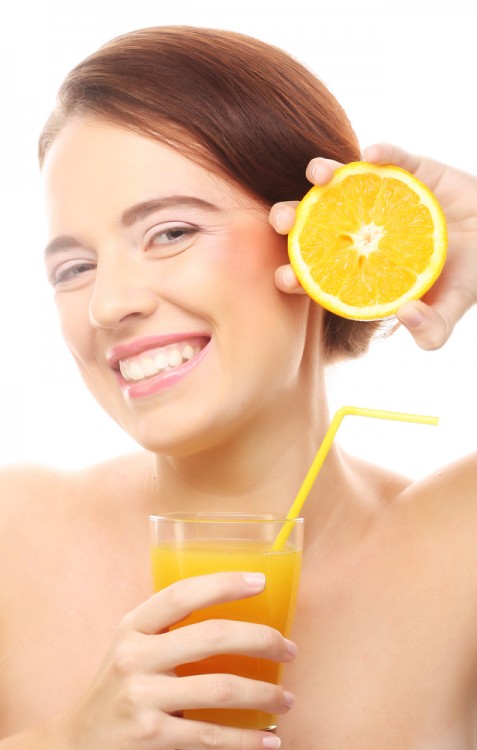 Woman holding an orange and a glass of orange juice in her hands. 