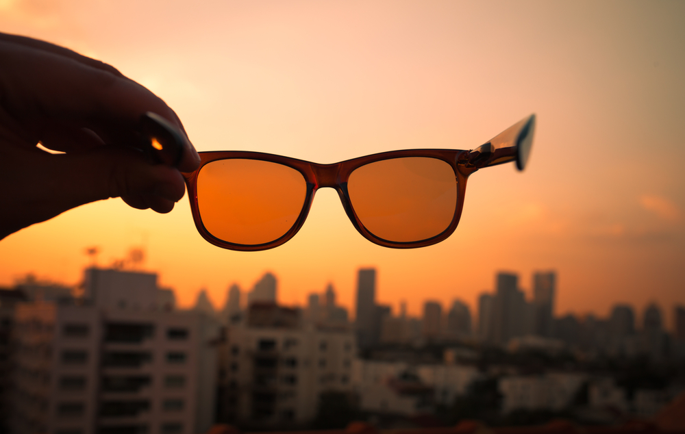 Woman holding orange colored glases