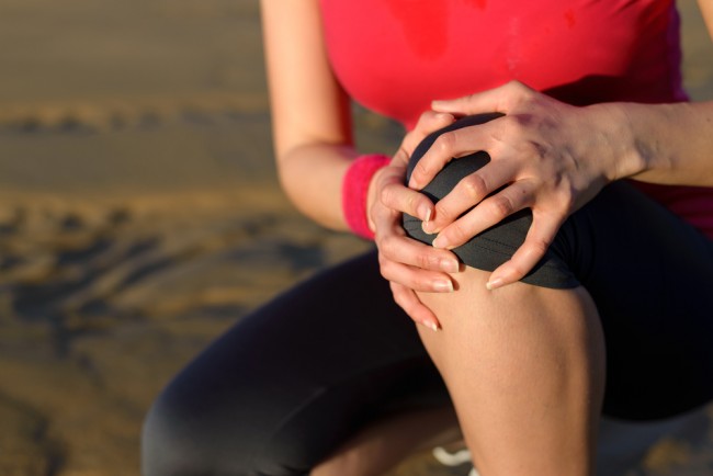 Woman suffering from joint pain while jogging. 