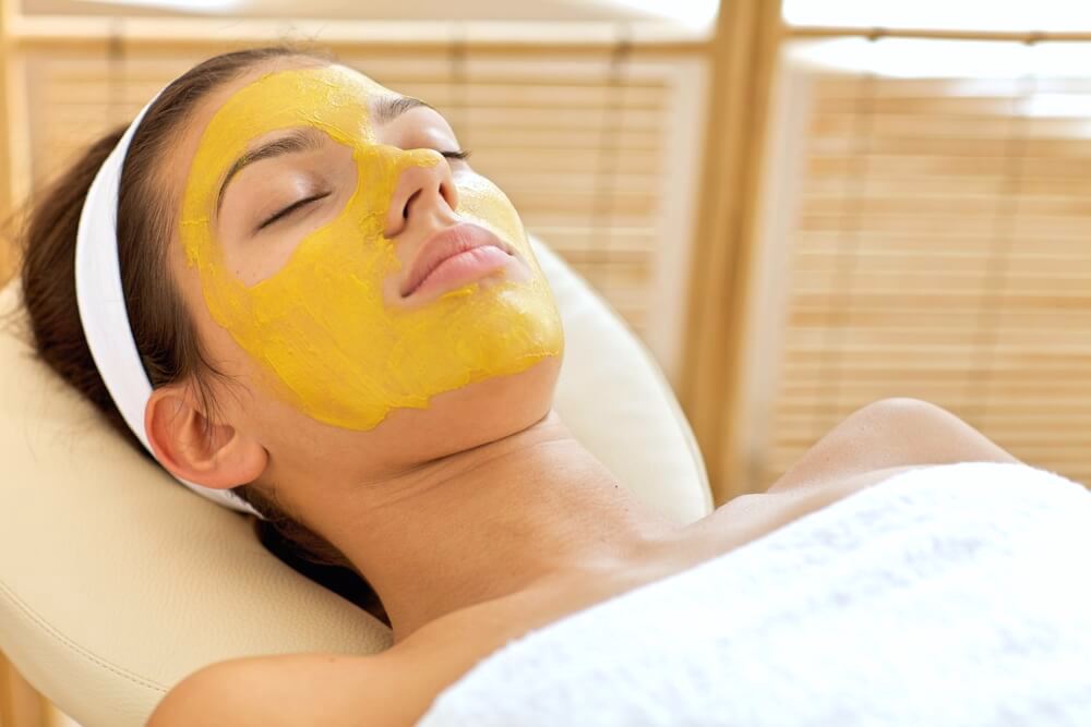 Calm woman relaxing with turmeric facial mask 