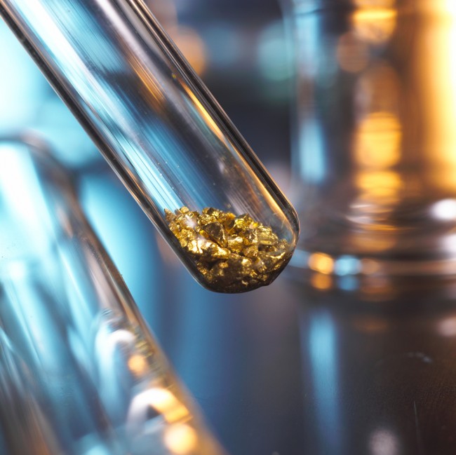 Scientist holding gold in a test tube in a research laboratory. 