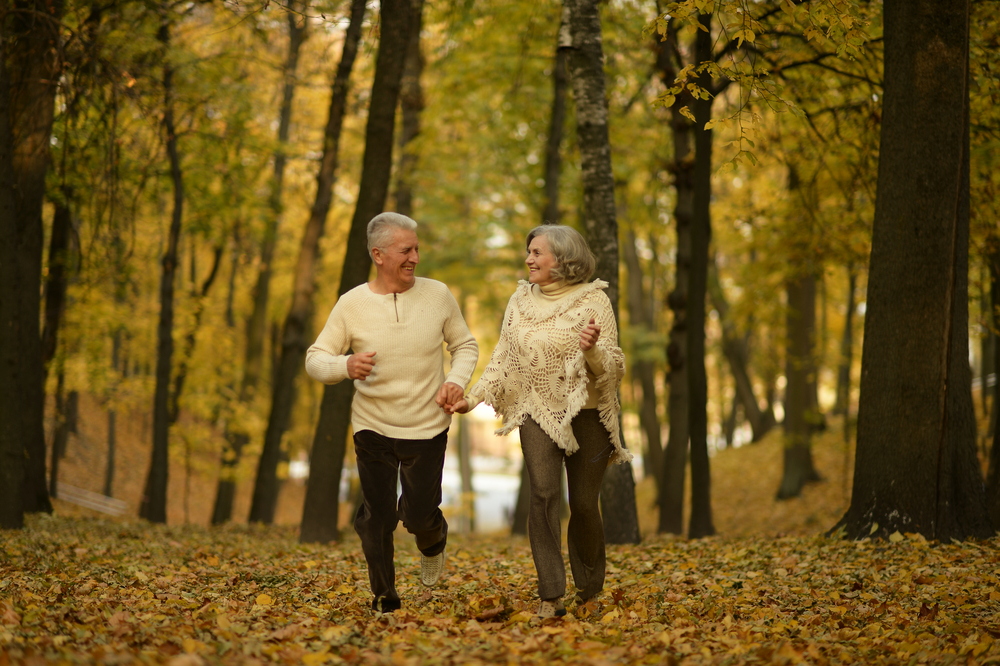 Mature couple jogging in the woods during fall. 