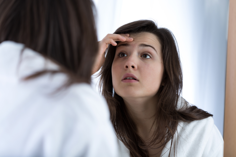 Woman examining acne