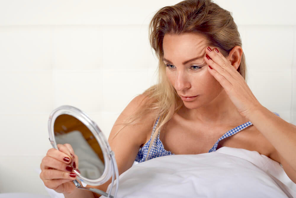 Woman checking her wrinkles in a handheld mirror