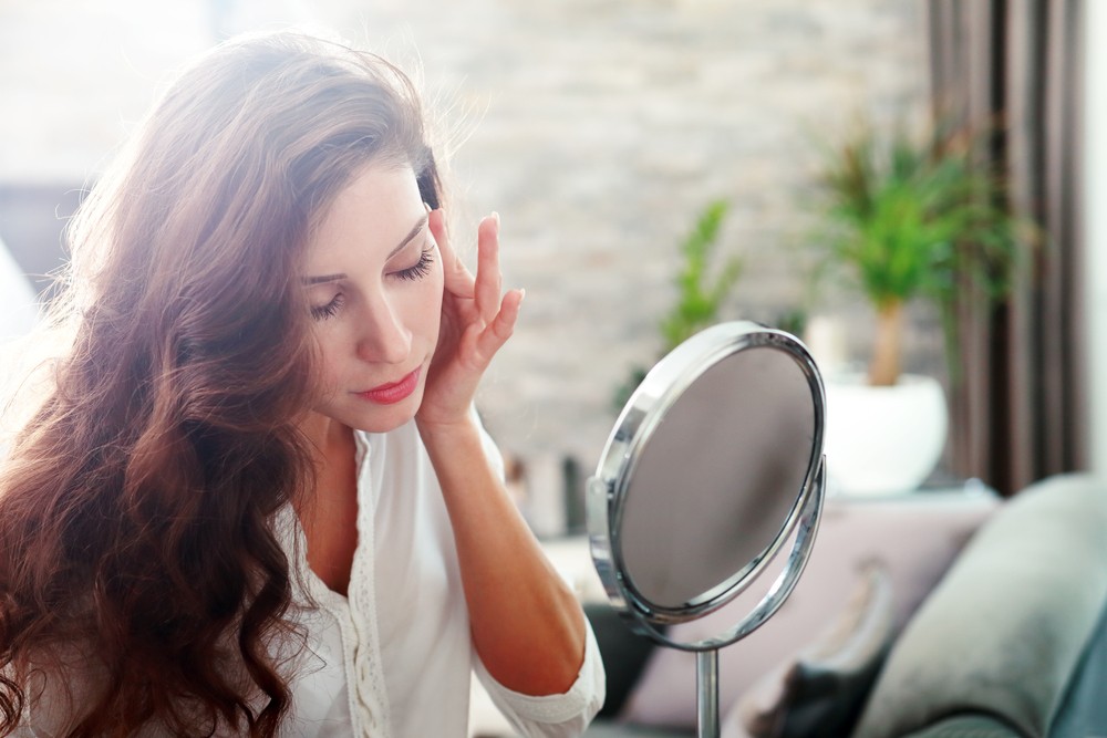 young beautiful woman looking into mirror