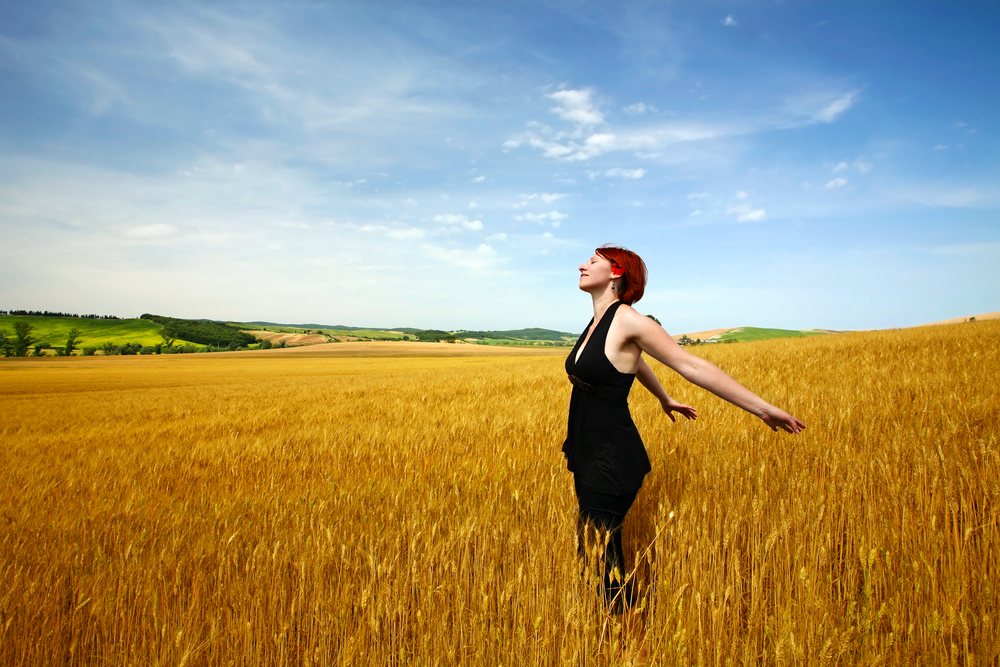 Woman spreading arms out in cereal field