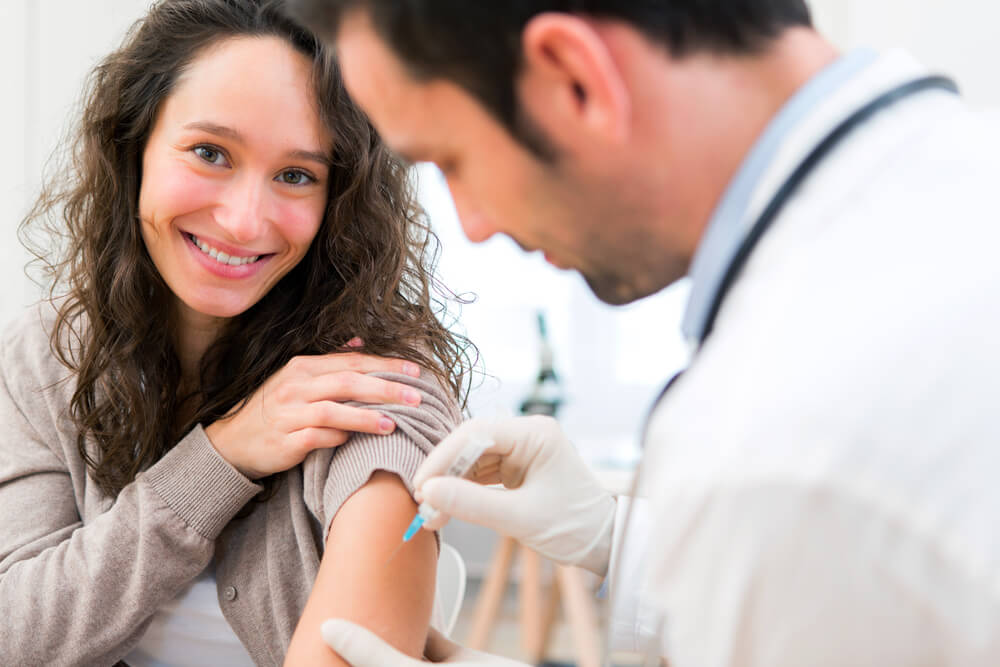Smiling woman getting an injection from a doctor