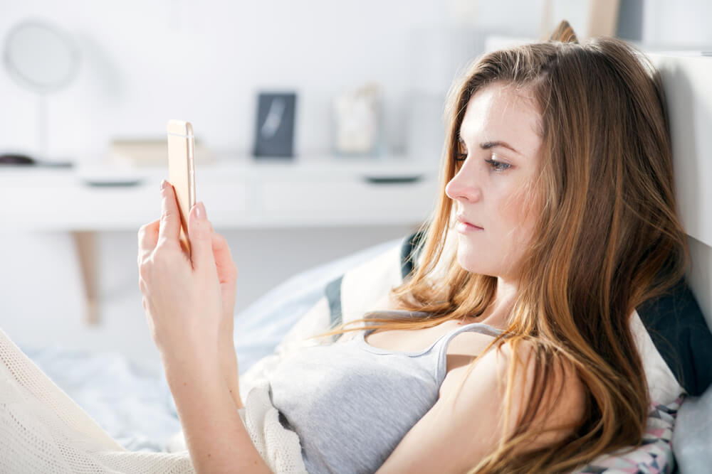 Woman checking her smartphone while in bed