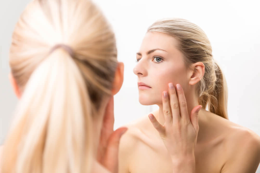 Woman examining her face in mirror