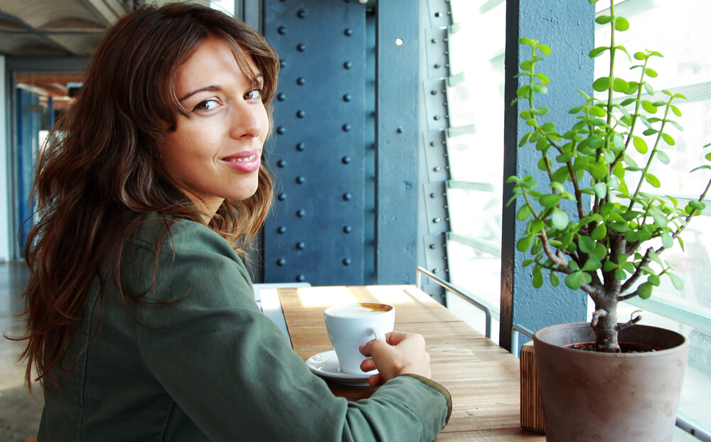 Woman looking over her shoulder with a cup of coffee