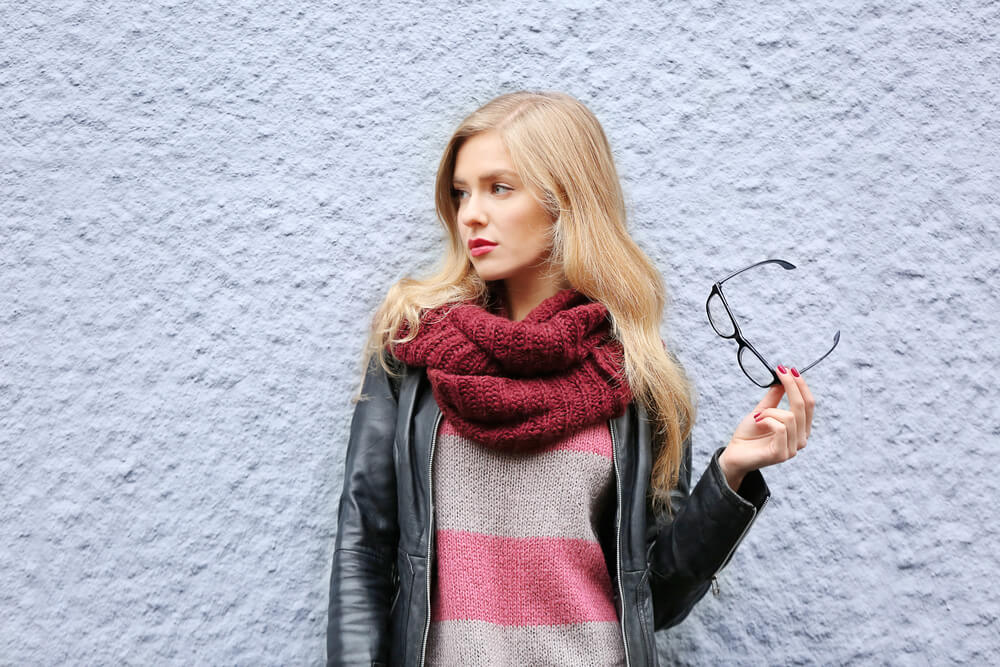 Woman with scarf holding her glasses 