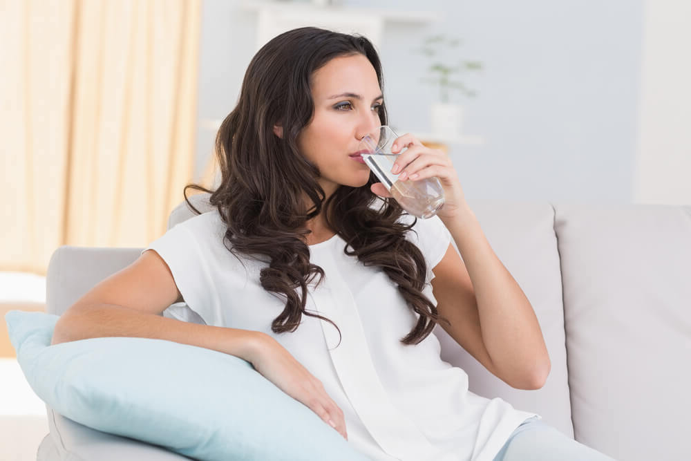 Woman drinking a glass of sparkling water at home