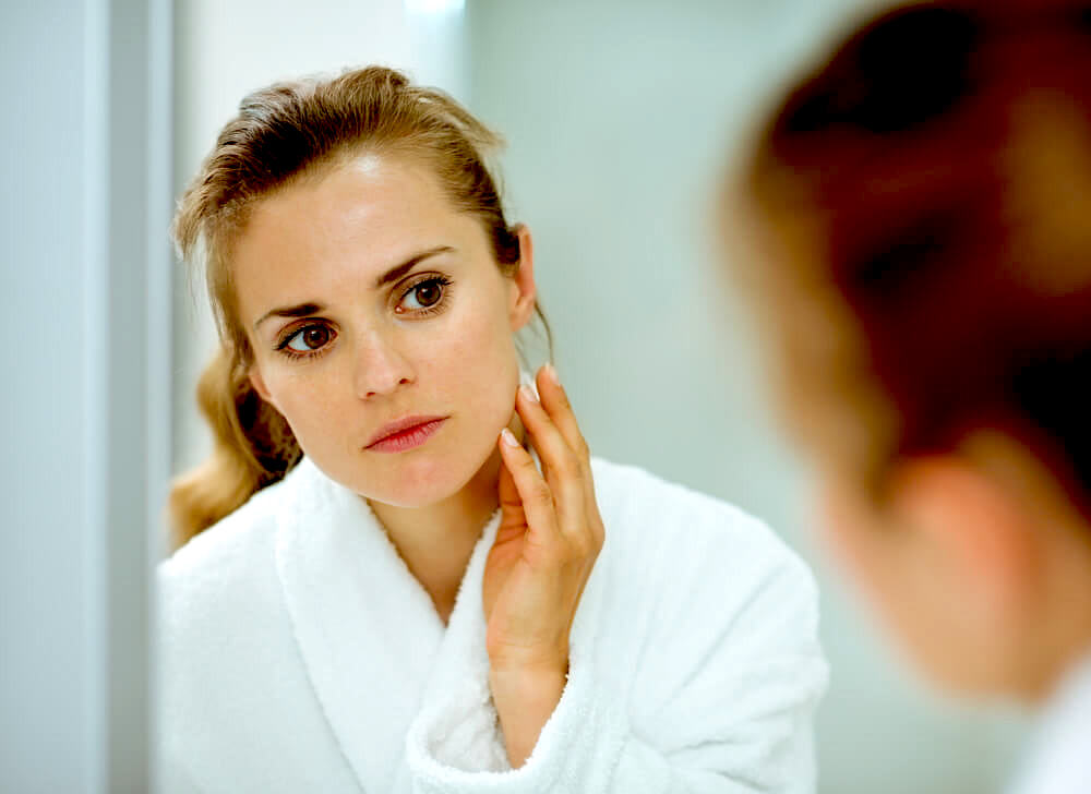 woman checking skin in the mirror