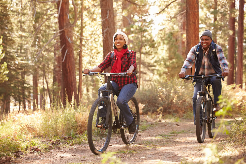 senior couple biking through fall woodlands