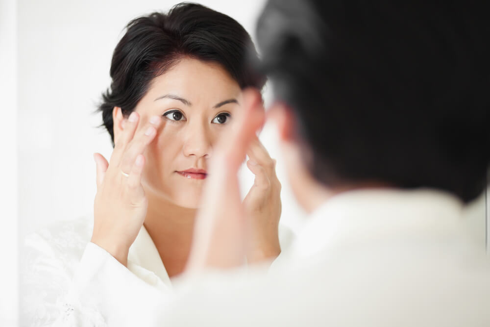 woman checking face in the mirror