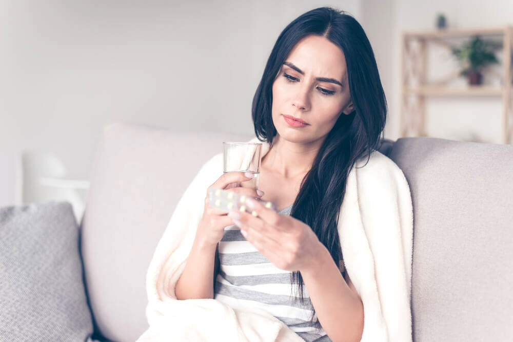 woman taking medication with a glass of water