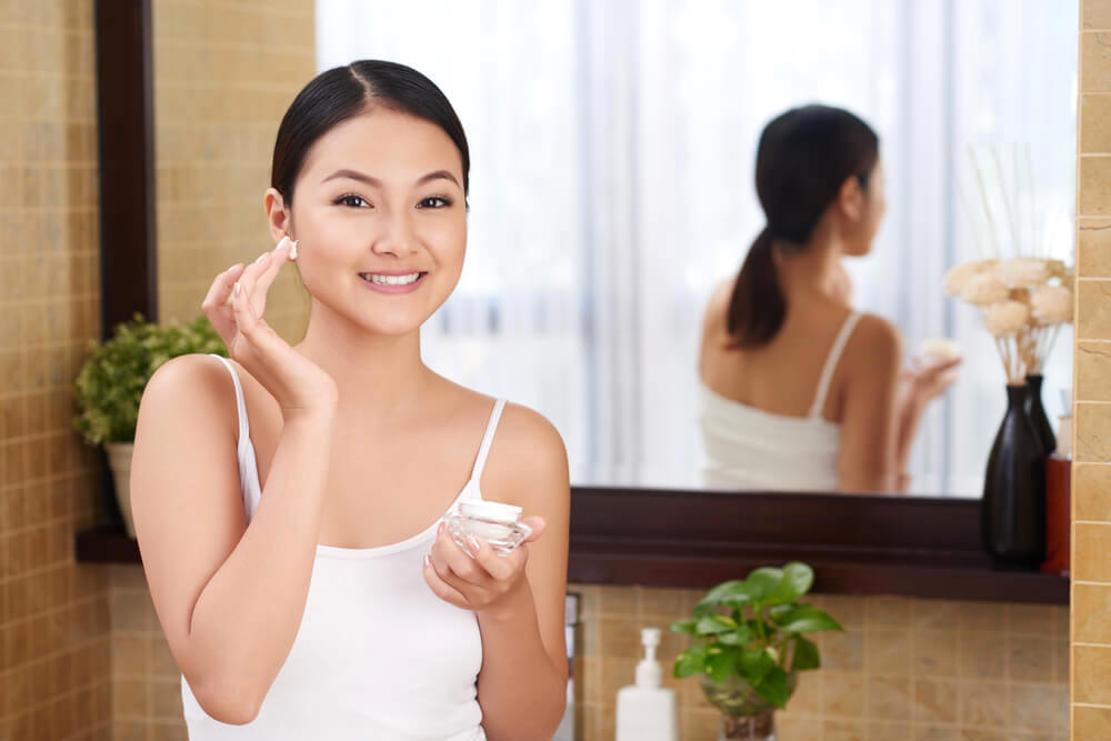 woman applying face moisturizer