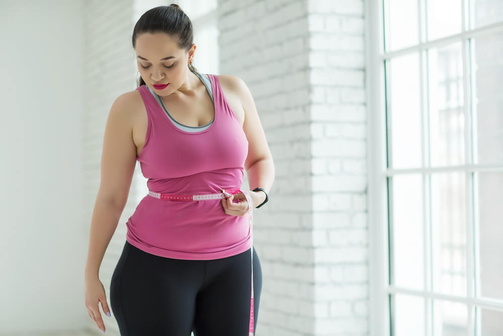 Woman measuring her waist, in athletic wear 