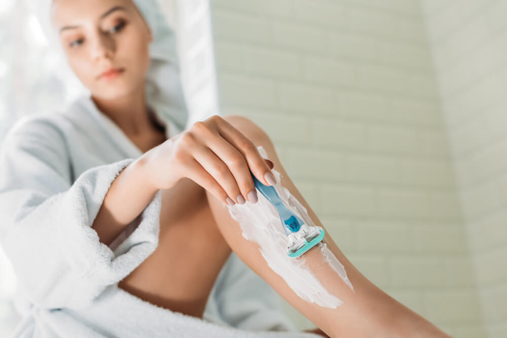 Woman shaving legs, using shaving cream